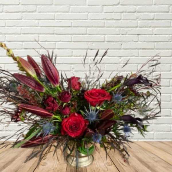 Red roses and burgundy lilies in a low vase arrangement