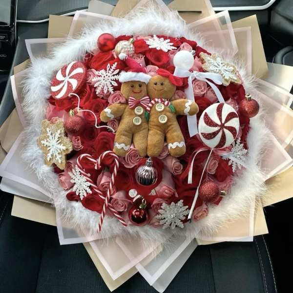 Holiday bouquet with red roses, candy ornaments, and two gingerbread figures