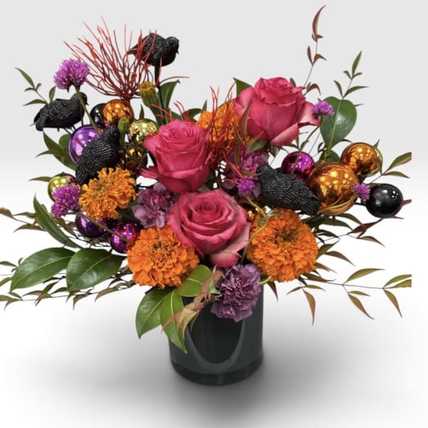 Pink roses and orange flowers in a black vase with decorative ornaments