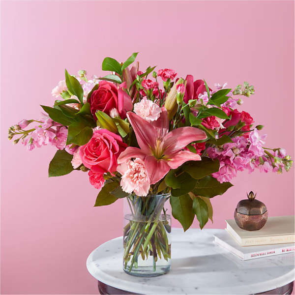 Pink bouquet of roses, lilies, and carnations in a glass vase