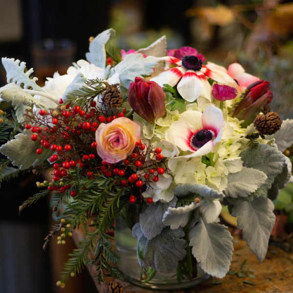 Bouquet of white and pink flowers with red berries in a glass vase