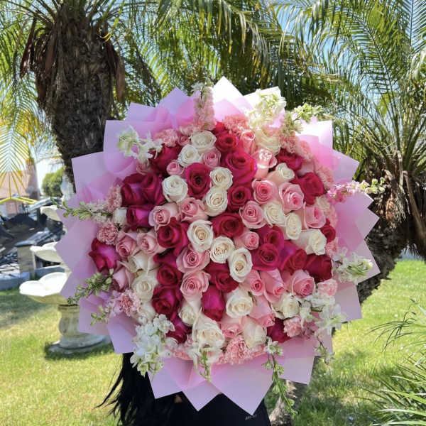 Large bouquet of pink, white, and red roses wrapped in pink paper