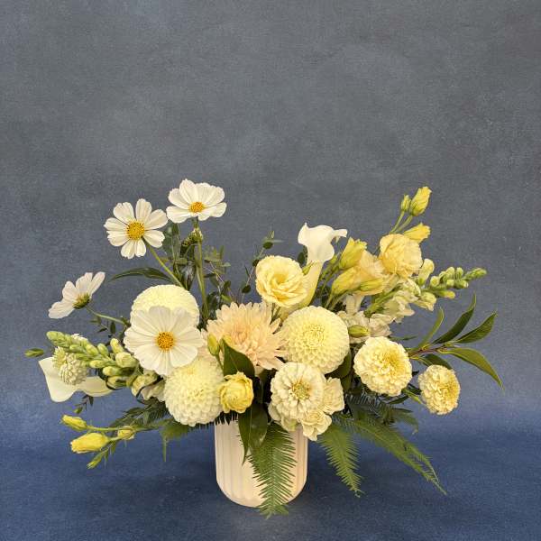 Cream and yellow floral arrangement in a white vase