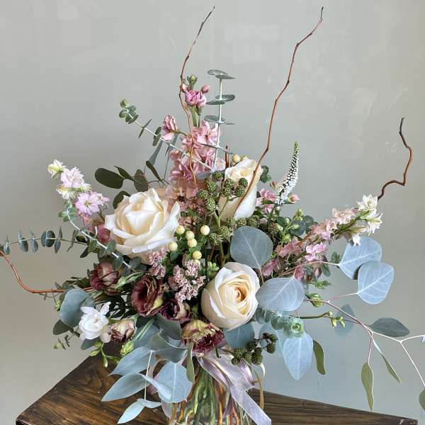 Tall bouquet of cream roses and pink flowers in a glass vase