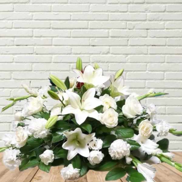 White lily and rose arrangement with green buds on a low base