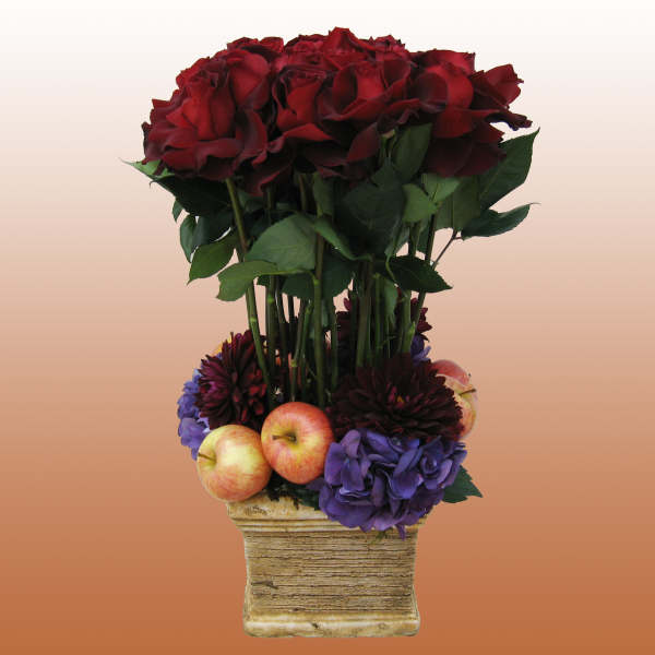 Red roses in a square vase with apples and purple flowers