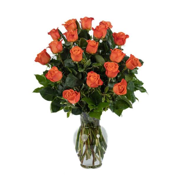 Tall arrangement of orange roses with lush foliage in a clear glass vase