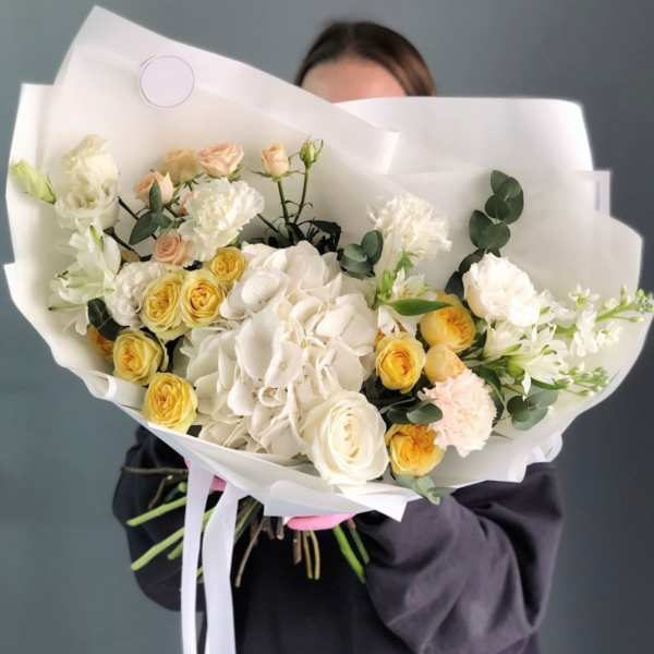 Bouquet of white and yellow roses with white hydrangea in white paper