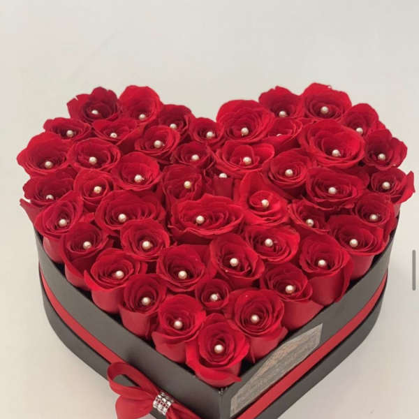 Heart-shaped box filled with red roses and pearl accents