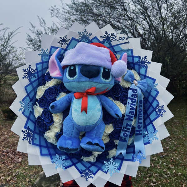 Blue plush character in a Santa hat surrounded by blue and white roses