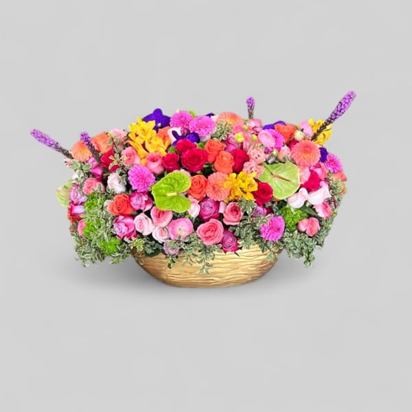 Colorful mixed flower arrangement in a low gold basket
