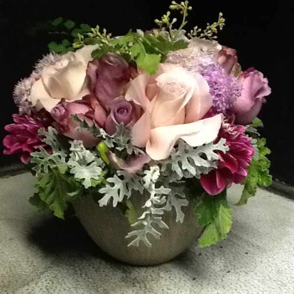 Mixed pink and white roses in a round vase with silver foliage