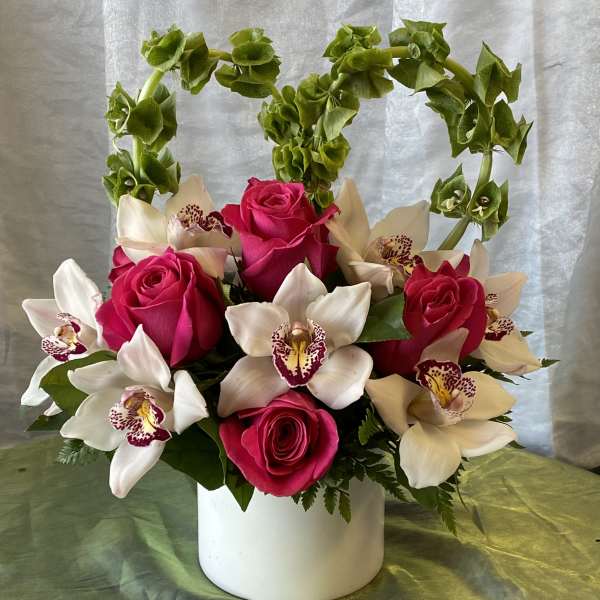 Pink roses and white orchids arranged in a white vase