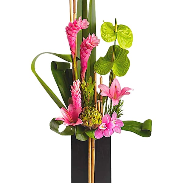 Pink tropical flowers arranged in a tall black vase with bamboo accents