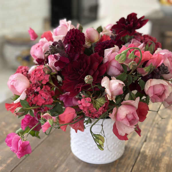Pink and burgundy flowers arranged in a white vase