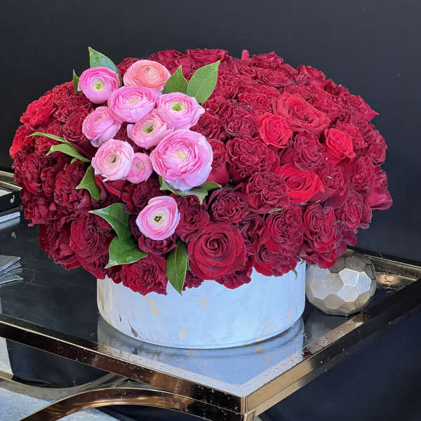 Large red and pink rose arrangement in a round white box