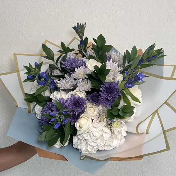 Bouquet of white and purple flowers wrapped in pastel paper