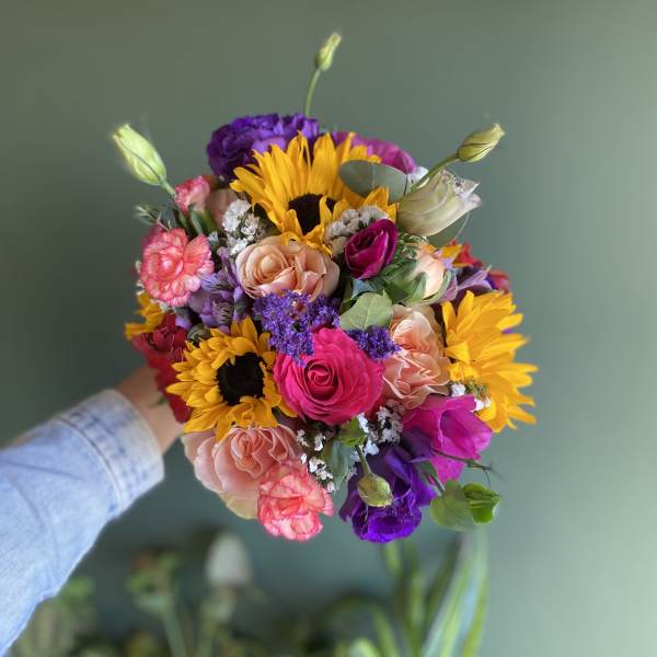 Handheld bouquet with sunflowers, roses, and purple blooms
