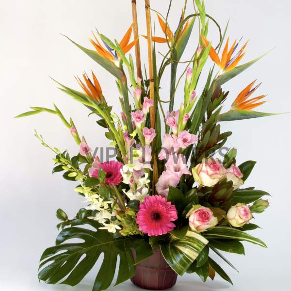 Tall tropical flower arrangement with orange bird of paradise and pink blooms in a basket