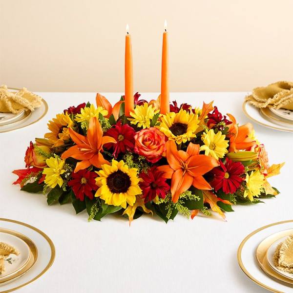 Autumn centerpiece with orange candles and mixed flowers on a table