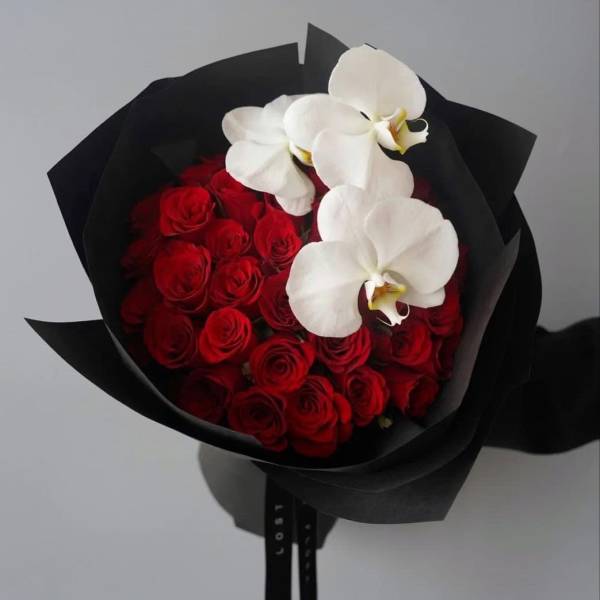 Bouquet of red roses with white orchids wrapped in black paper