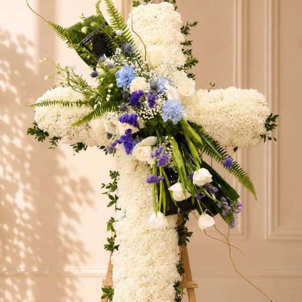 Large white floral cross on an easel with blue and purple accents