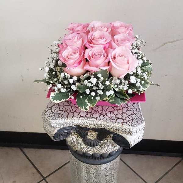 Pink roses arranged in a decorative pedestal container