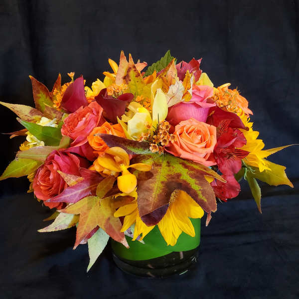 Autumn bouquet of roses, calla lilies, and sunflowers in a green vase