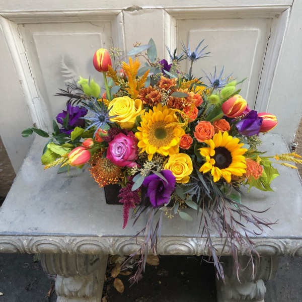 Colorful mixed bouquet with sunflowers, roses, and tulips in a black container