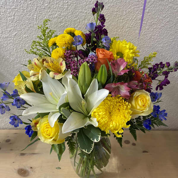 Mixed bouquet of lilies, roses, and bright flowers in a glass vase