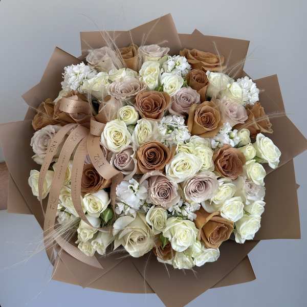 Bouquet of cream, blush, and caramel roses wrapped in brown paper