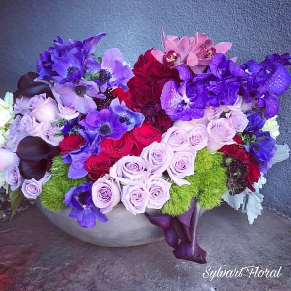 Colorful floral arrangement in a low bowl with roses and purple blooms