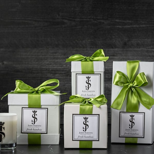 Gift boxes with green ribbons, a candle, and white flowers in a vase