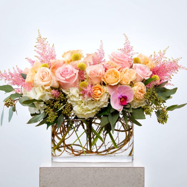 Pink and peach roses in a glass vase with pink filler flowers