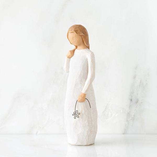 Wooden angel figurine in a white dress holding a small flower