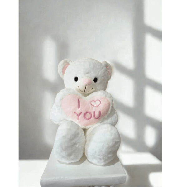 White teddy bear holding a pink heart that says I love you