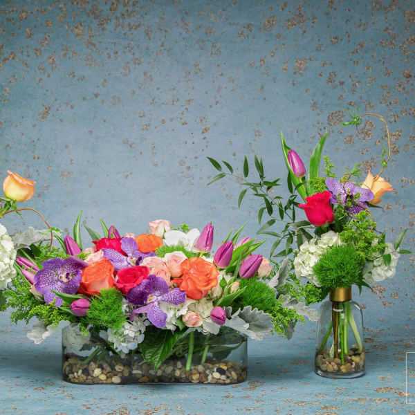 Three colorful floral arrangements in glass vases and a low rectangular container
