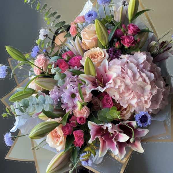Mixed bouquet with pink roses, lilies, and hydrangea in paper wrap