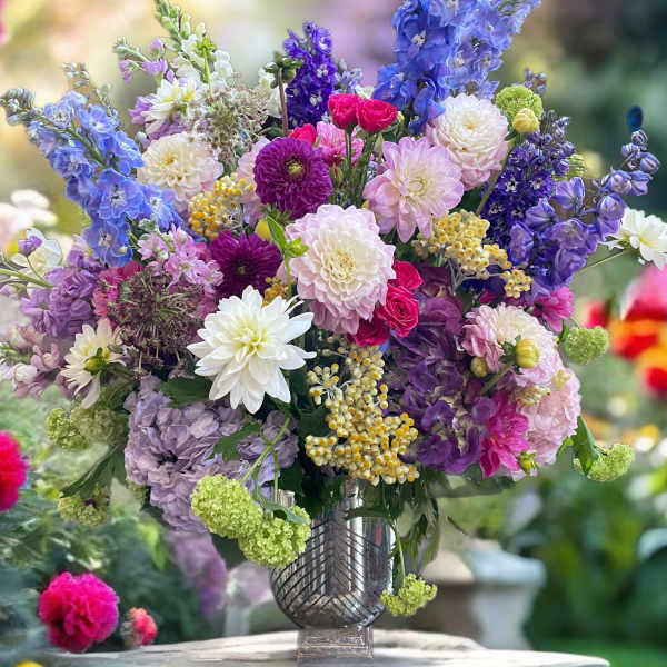 Colorful mixed bouquet in a clear vase with blue, purple, pink, and white blooms