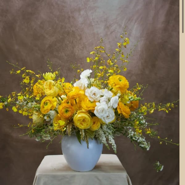 Yellow and white flower arrangement in a white vase