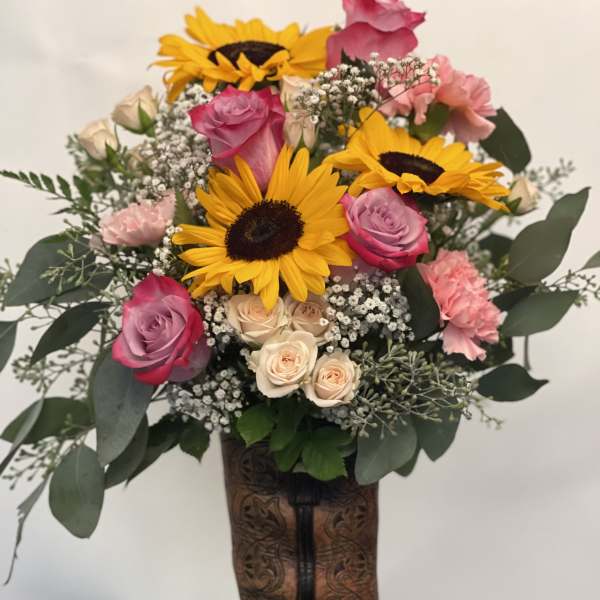Bouquet of sunflowers, pink roses, and carnations in a cowboy boot vase