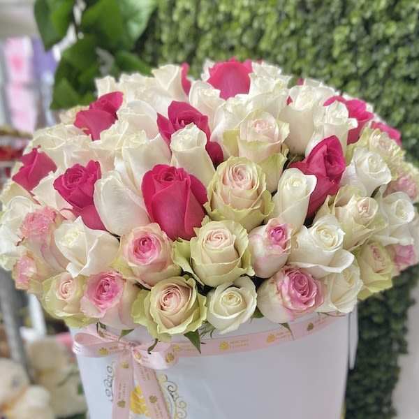 Round hatbox of white, pink, and blush roses tied with a pink ribbon