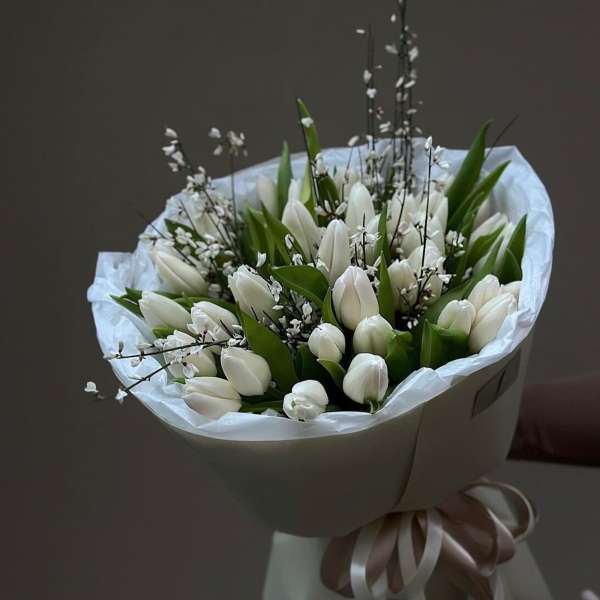 Bouquet of white tulips wrapped in white paper with a ribbon