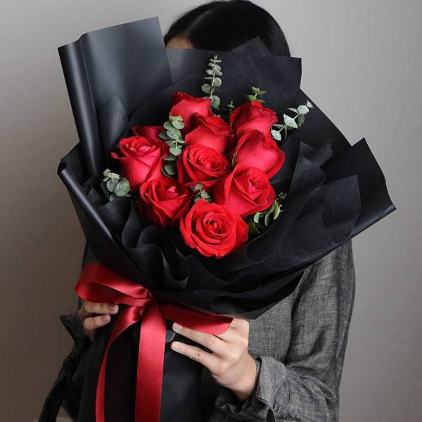 Bouquet of red roses wrapped in black paper with a red ribbon