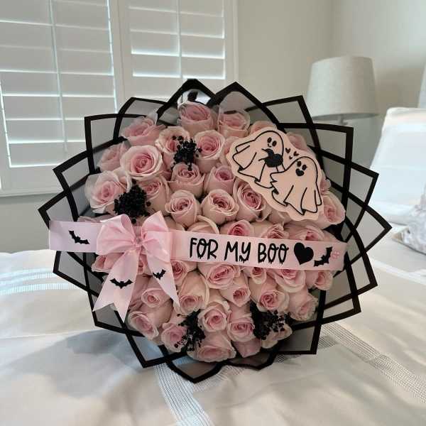Bouquet of pink roses with a pink ribbon and Halloween ghost decorations