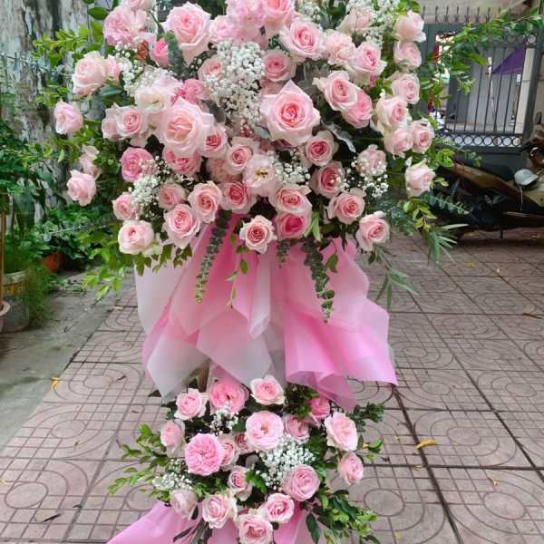 Large pink rose arrangement with white filler flowers and pink draping