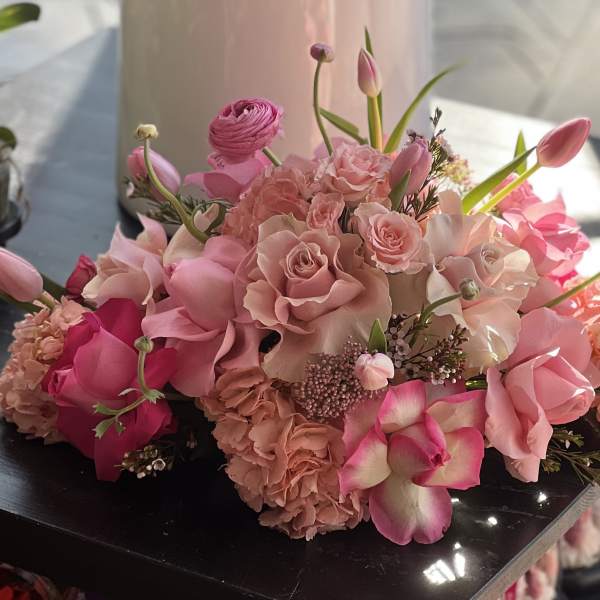Pink bouquet with roses, tulips, and orchids arranged low and full