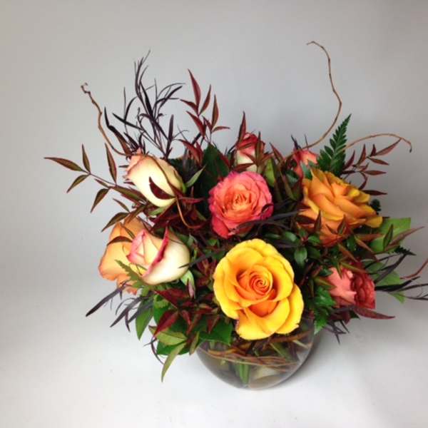 Arrangement of multicolored roses in a clear glass bowl