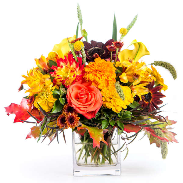 Autumn bouquet of orange and yellow flowers in a clear glass vase