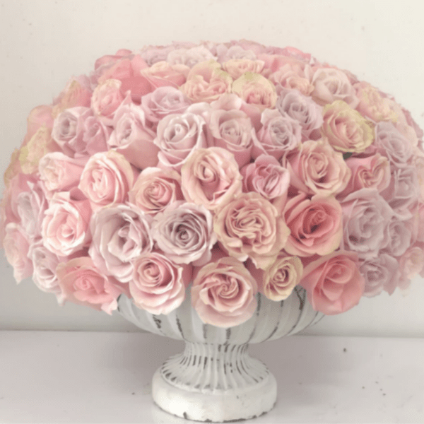 Round bouquet of pale pink roses in a white pedestal vase